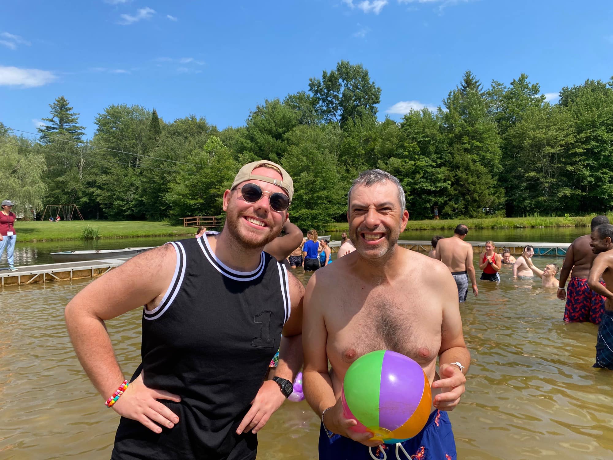 Gabriel Homes resident (right) holding a beach ball at a lake at Camp Jaycee.