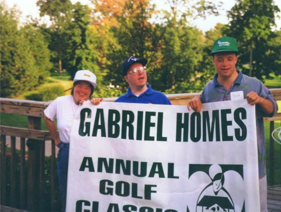 Gabriel Homes residents holding up a banner for the annual golf tournament.