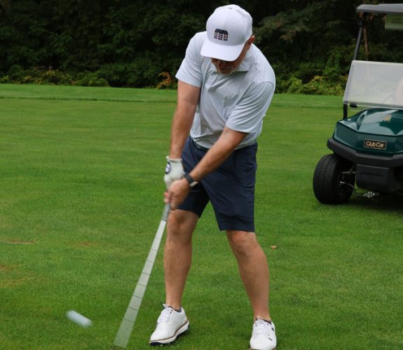 Golfer swinging club at the Gabriel Homes Golf Tournament.