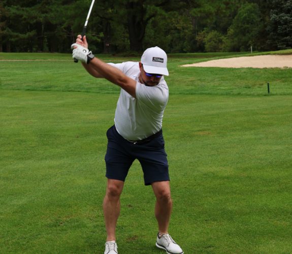 Golfer swinging club at the Gabriel Homes Golf Tournament.