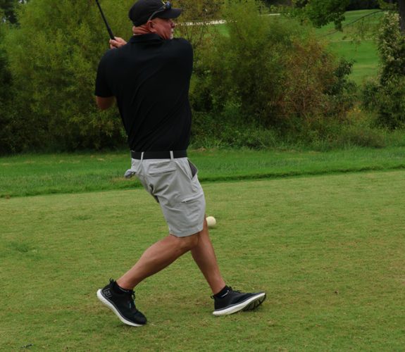 Golfer swinging club at the Gabriel Homes Golf Tournament.