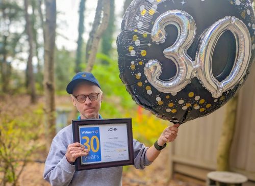 Gabriel Homes resident holding a Walmart 30-year work anniversary certificate and a "30" balloon.