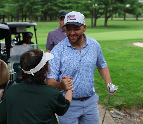 Golfer (center) shaking hands with Gabriel Homes resident (left).