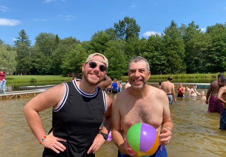 Gabriel Homes resident (right) holding a beach ball at a lake at Camp Jaycee.
