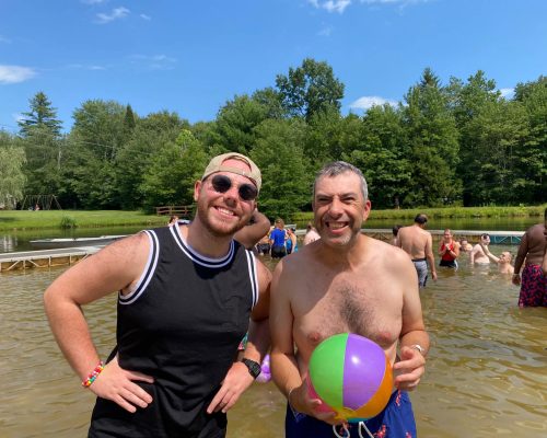 Gabriel Homes resident (right) holding a beach ball at a lake at Camp Jaycee.