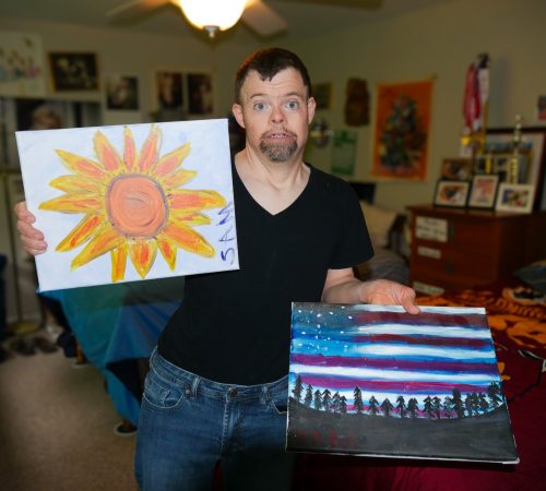 Gabriel Homes resident holding two canvases they painted.
